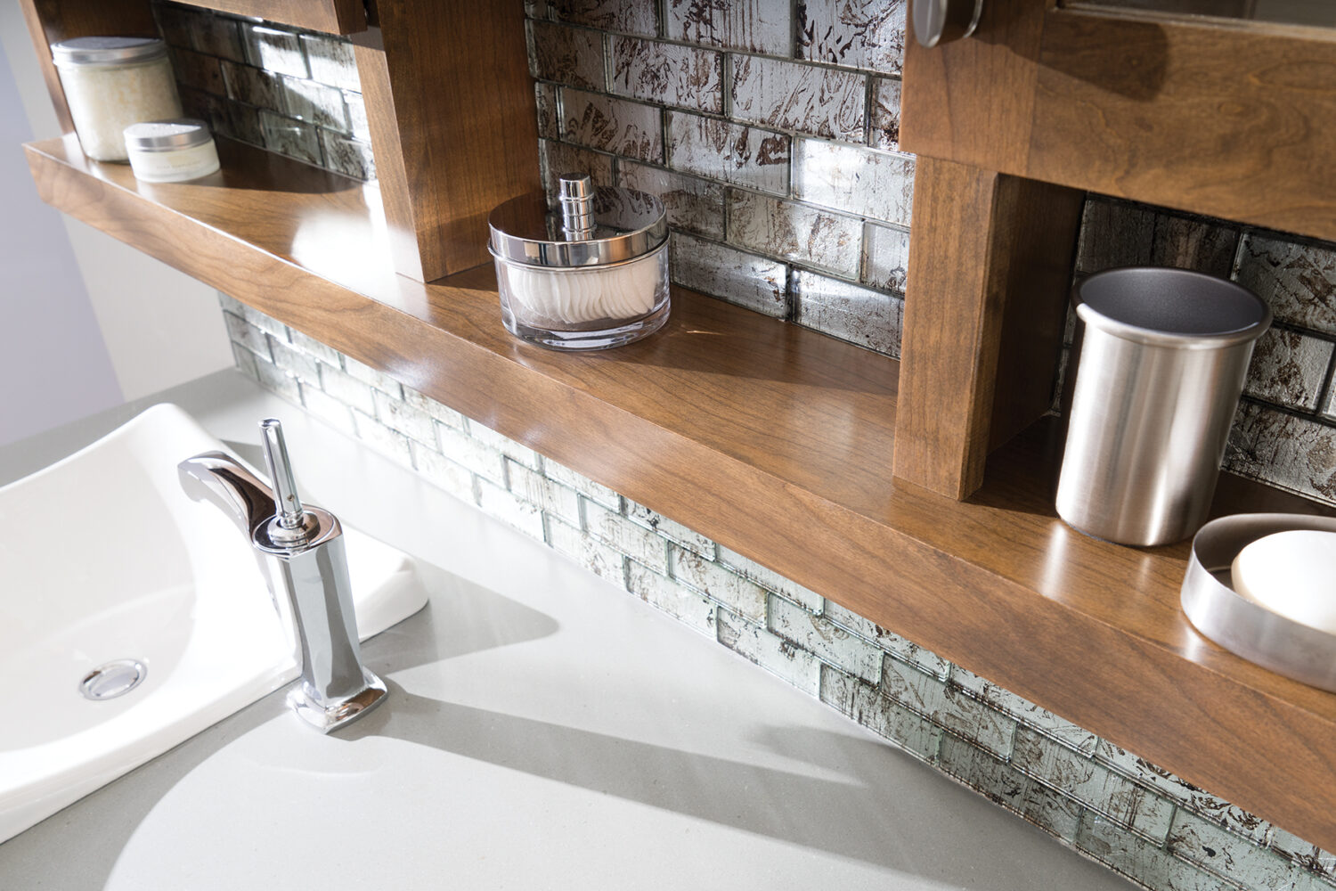 A close up of the floating shelves connected to a double vanity mirror in a modern master bathroom with an industrial style.