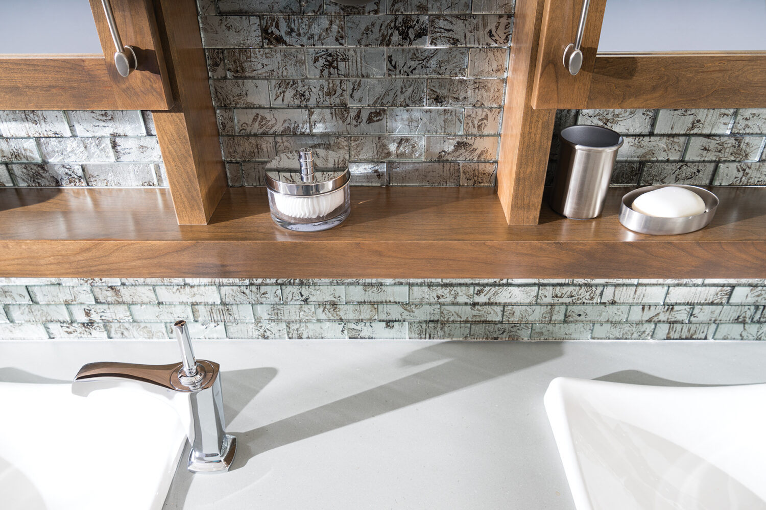 A close up of the floating shelves connected to a double vanity mirror in a modern master bathroom with an industrial style.