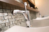 A modern bathroom faucet on a floating vanity cabinet by Dura Supreme Cabinetry.