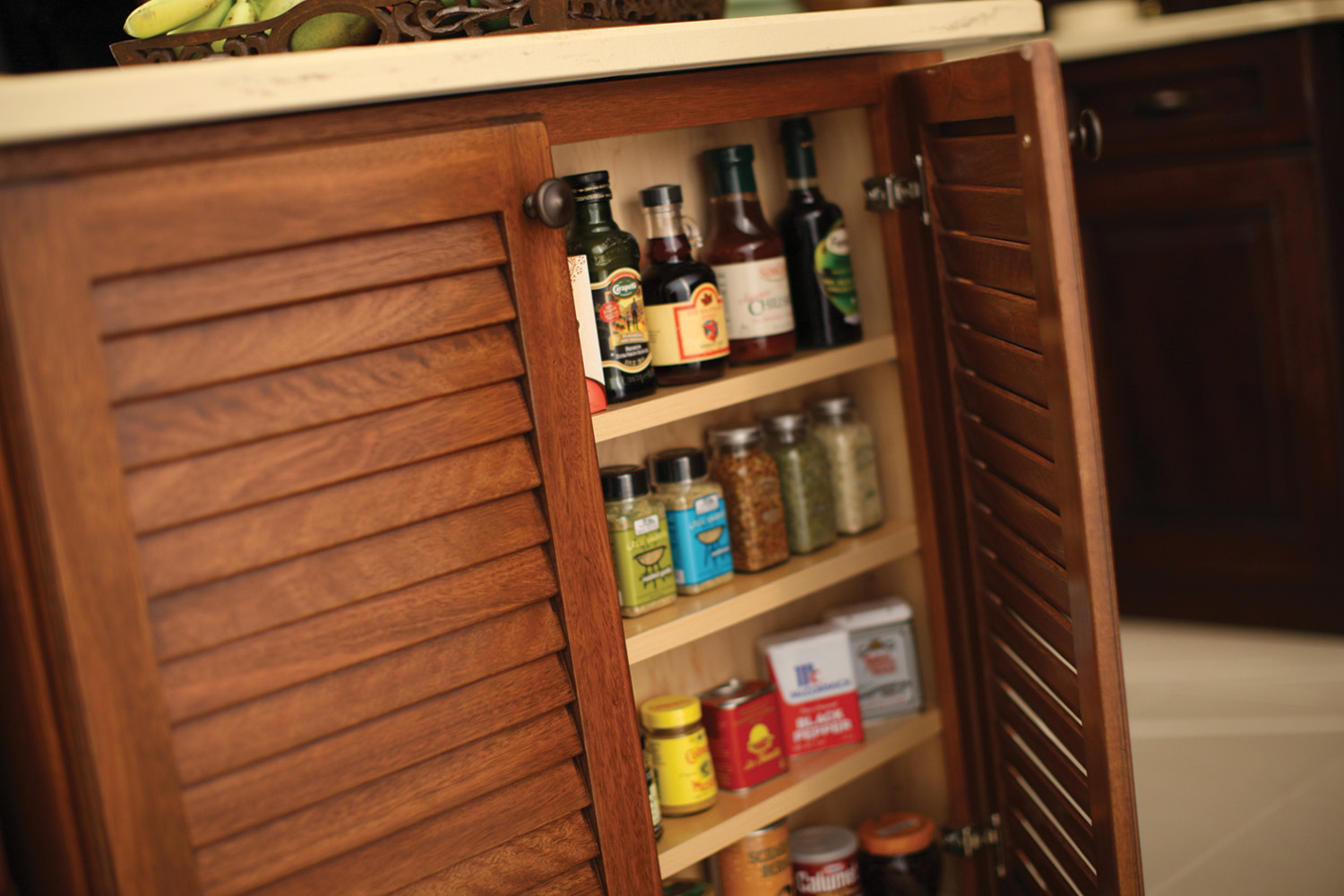 A Shallow Cabinet can be easily added to the end of an island or a peninsula creating a space fully dedicated to your spice collection. This tropical styled kitchen island features Dura Supreme Cabinetry.