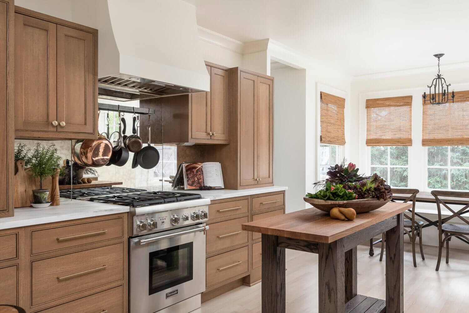 A Dutch style kitchen with American-made inset cabinets in a light stained oak wood. The modern white hood with the small table kitchen island captures the Scandinavian look.