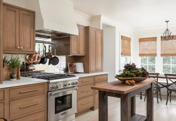 A Dutch style kitchen with American-made inset cabinets in a light stained oak wood. The modern white hood with the small table kitchen island captures the Scandinavian look.