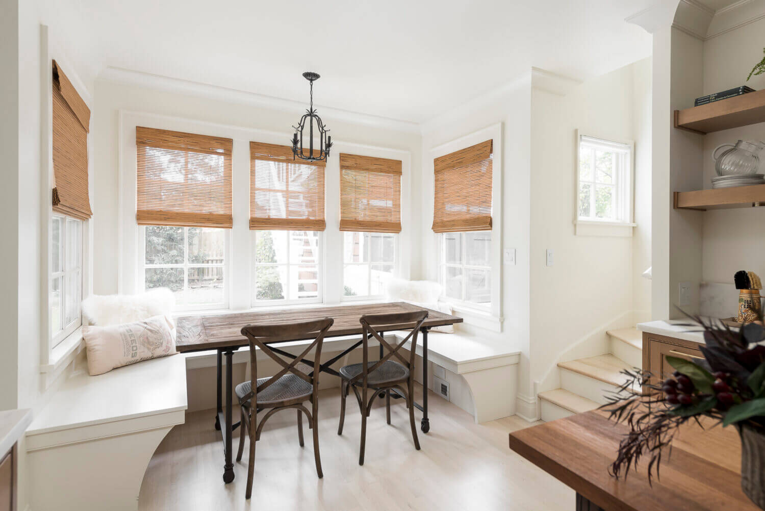 A beautiful Scandinavian styled breakfast nook area with built-in banquette seating in a white paint that matches the walls.