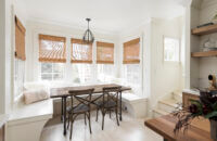 A beautiful Scandinavian styled breakfast nook area with built-in banquette seating in a white paint that matches the walls.