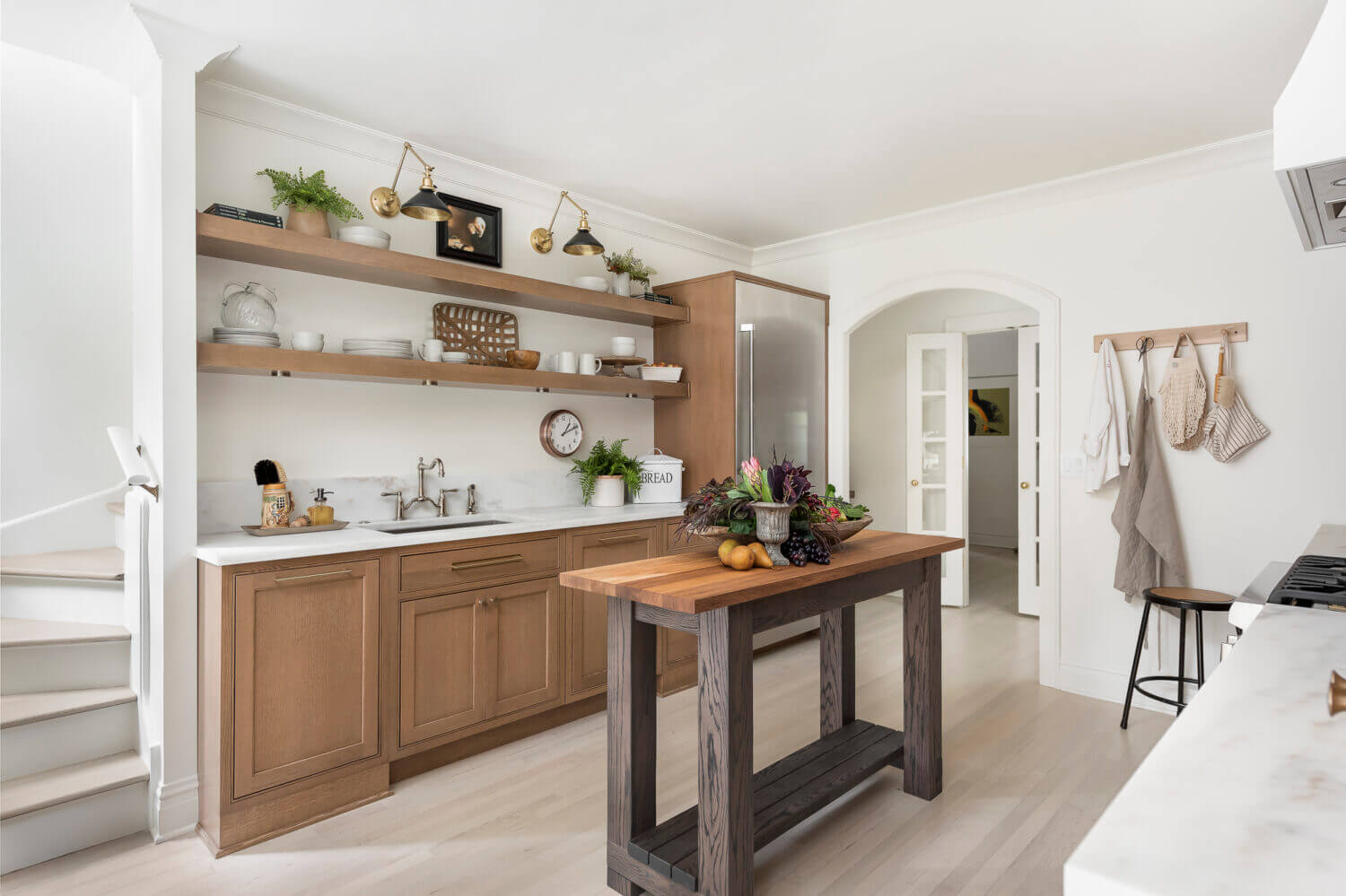 The sink wall of this kitchen has floating shelves above the sink for simplified, decorative storage.