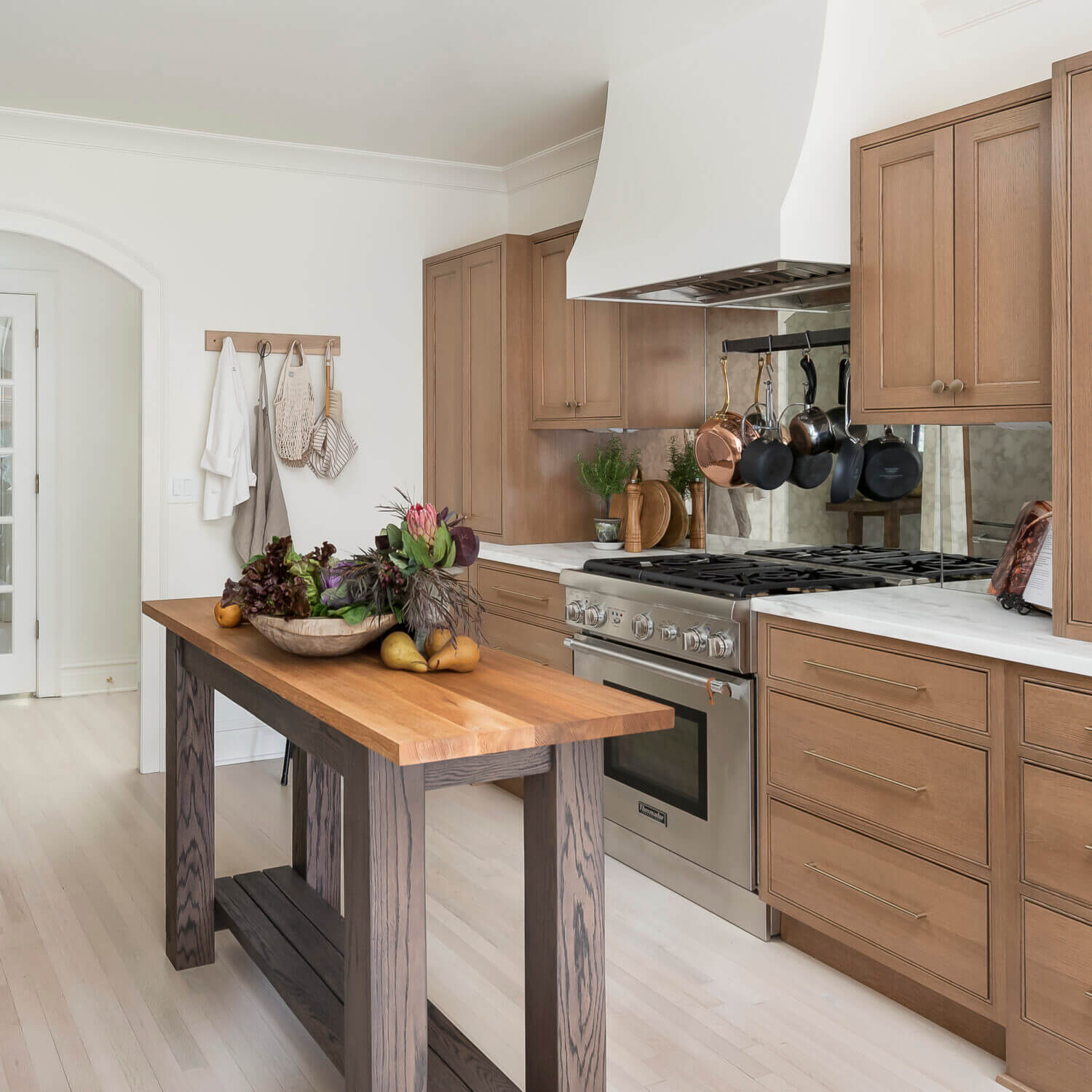 A Danish styled kitchen with light oak cabinets and a weathered kitchen island table.