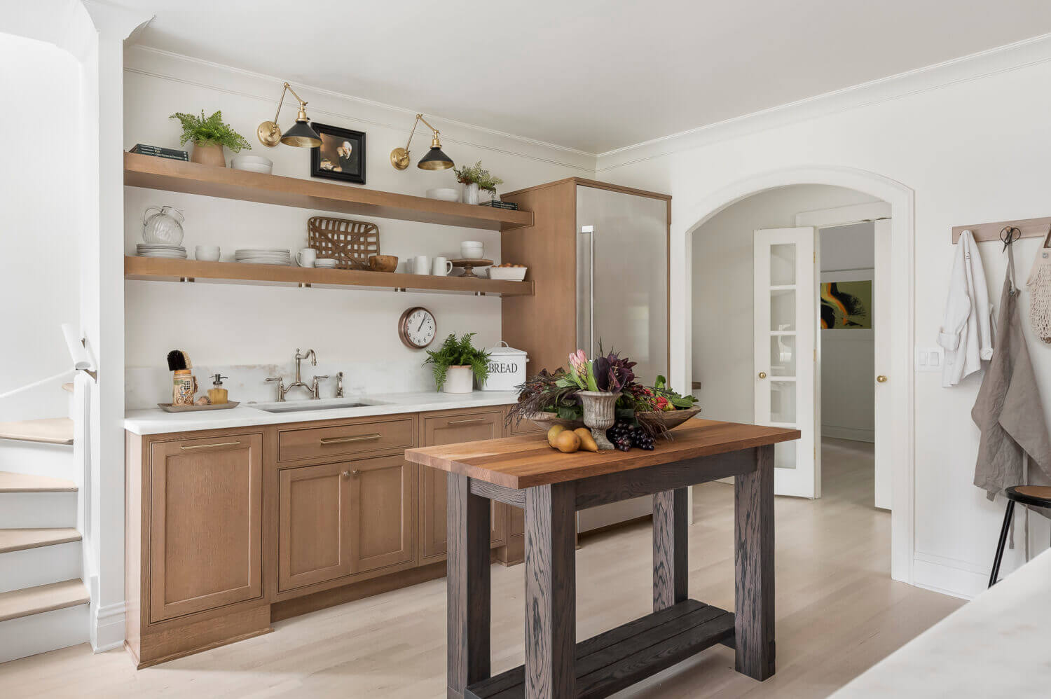 The sink wall of this kitchen has floating shelves above the sink for simplified, decorative storage.