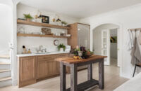 The sink wall of this kitchen has floating shelves above the sink for simplified, decorative storage.