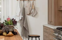 A simple coat hook rack that matches the kitchen cabinetry creates a simple and beautiful space for hanging garments near the kitchen entryway.