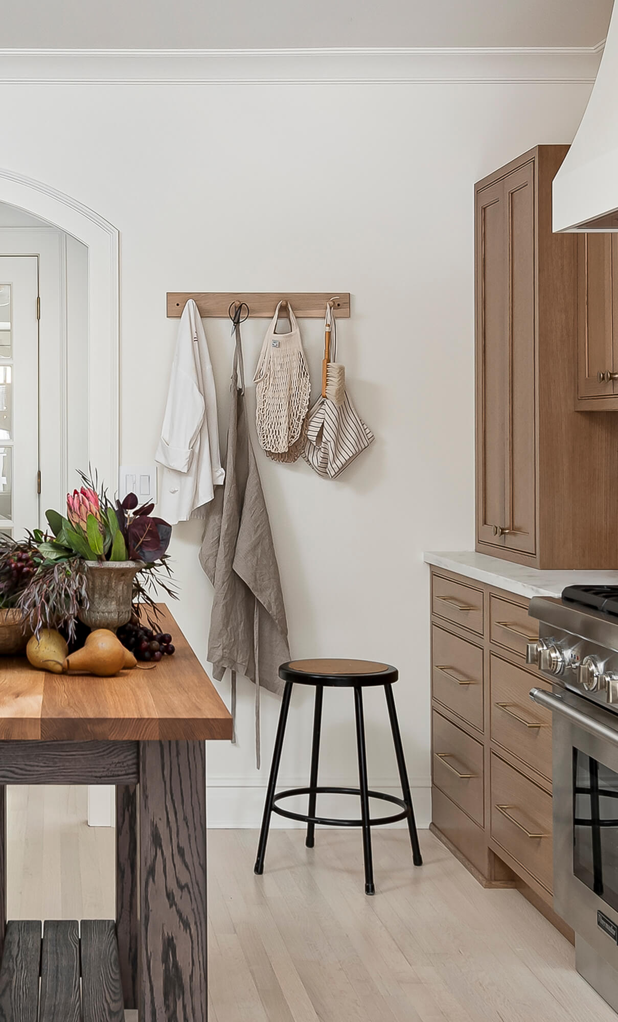 A simple coat hook rack that matches the kitchen cabinetry creates a simple and beautiful space for hanging garments near the kitchen entryway.