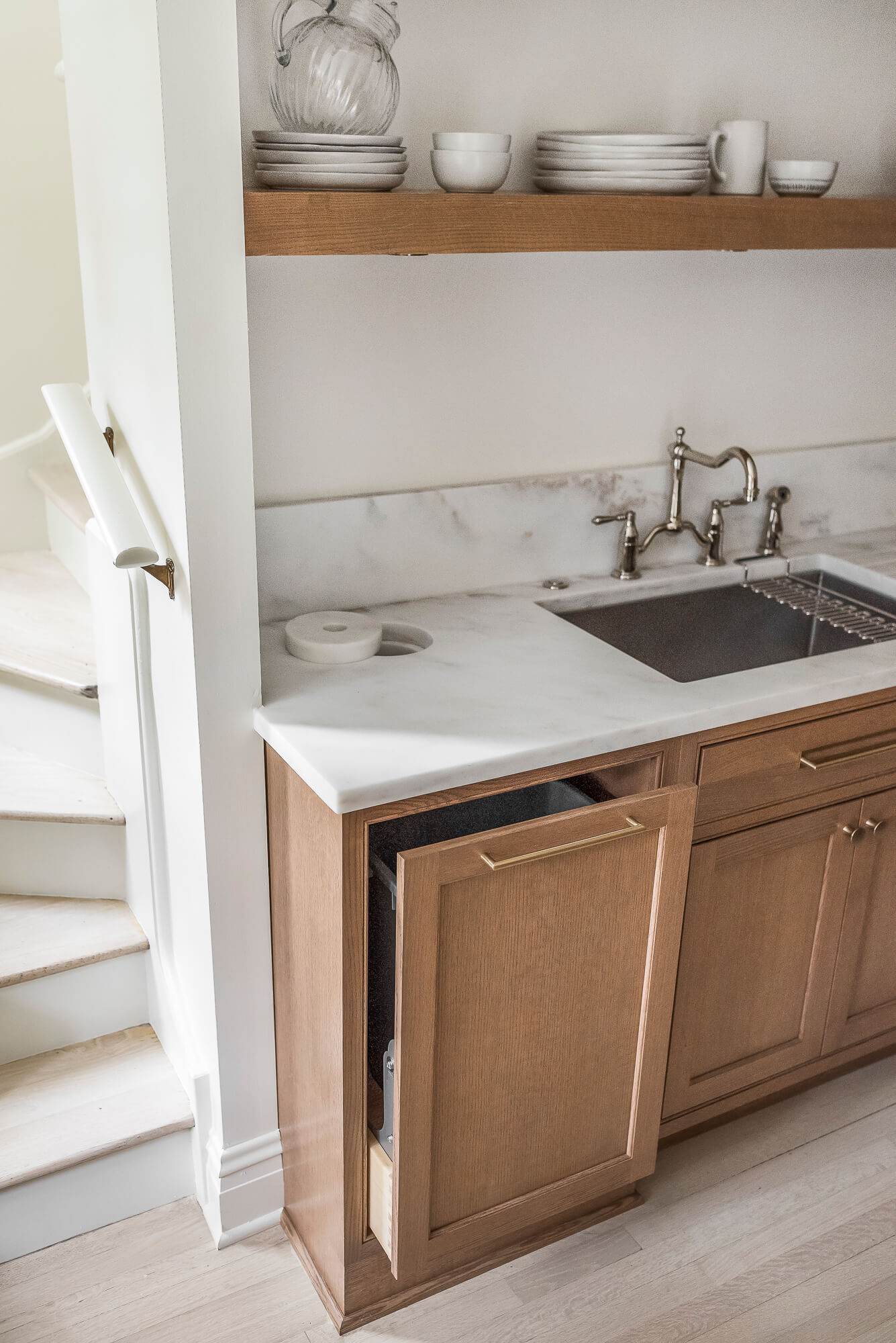 A base recycling pull-out cabinet with storage for a waste bin and recycling bin hidden in the cabinet.