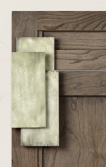 Learn about kitchen & bath cabinetry product lines to see which type of cabinet construction best suits your design needs. This images shows a close up of a detailed flat panel door style with a medium stained finish on Cherry wood with kale green subway tiles.