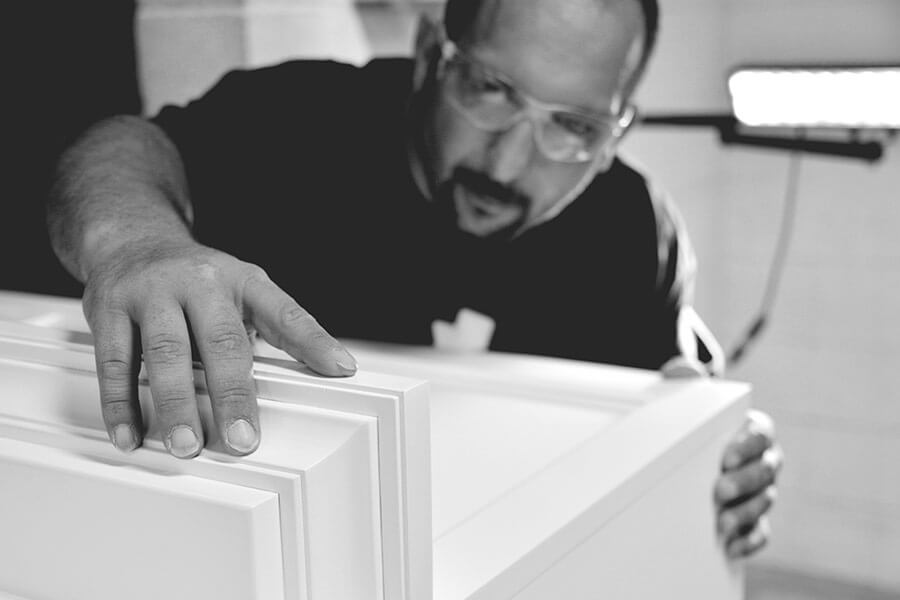 A professional cabinet maker quality inspecting the details of the kitchen cabinet products in the cabinet factory.