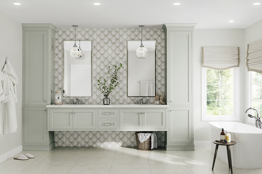 A transitional styled master bathroom desing with a floating vanity, two floor to ceiling linen cabinets capping off the end of both sides of the wall-hung vanity cabinets. The bath cabinets are shown in a beautiful light gray painted finish that is trendy and classic. Learn more about interior design styles and how to style kitchen and bath cabinetry to create a fresh look.