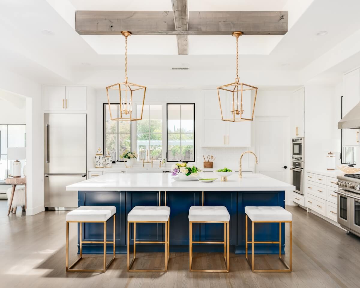 Trend setting navy blue and white kitchen with gold hadware and large-scaled pendant lights.