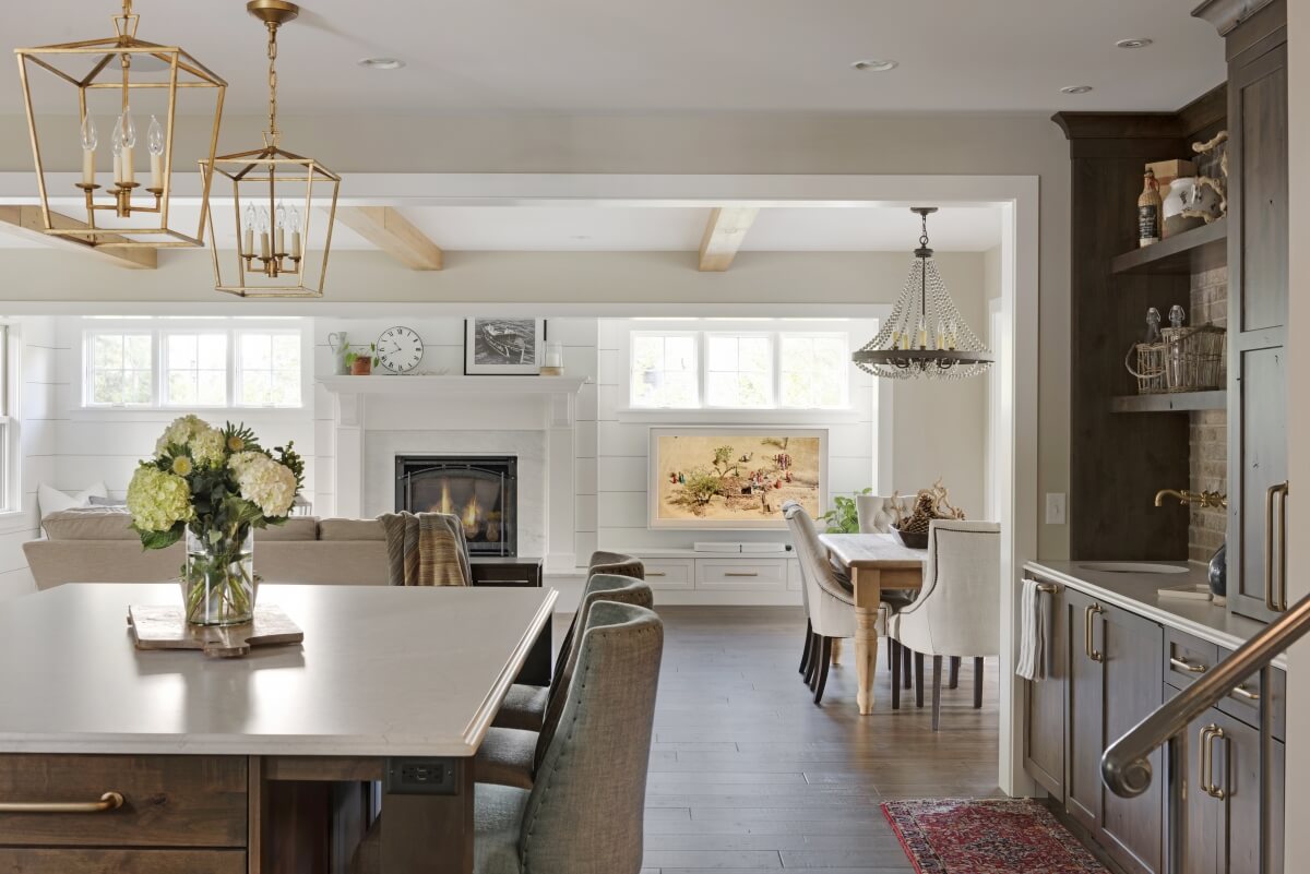 This kitchen features two grand sizes pendants over the kitchen island and 1 large chandelier over the dining room table to define the 2 spaces in the open floor plan. Dura Supreme design by Studio M Kitchen & Bath.
