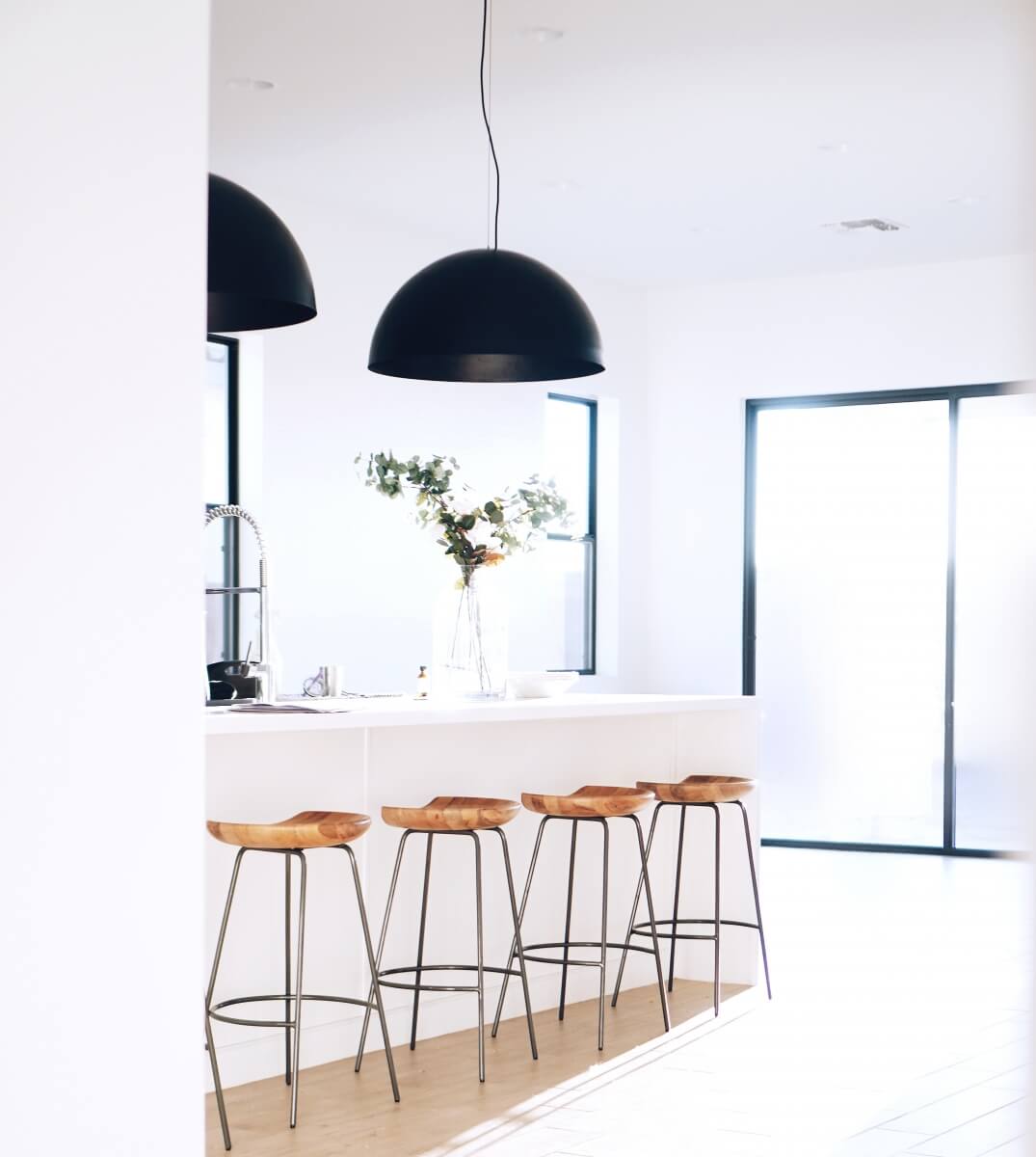 An example of a kitchen design trend. Two overzied black light shades on pendant lights over a kitchen island. Kitchen design trends to consider.