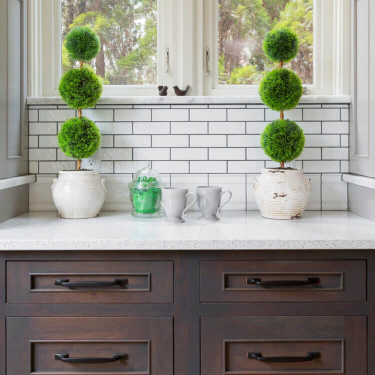 A pretty kitchen window space with gray stained inset cabinets.