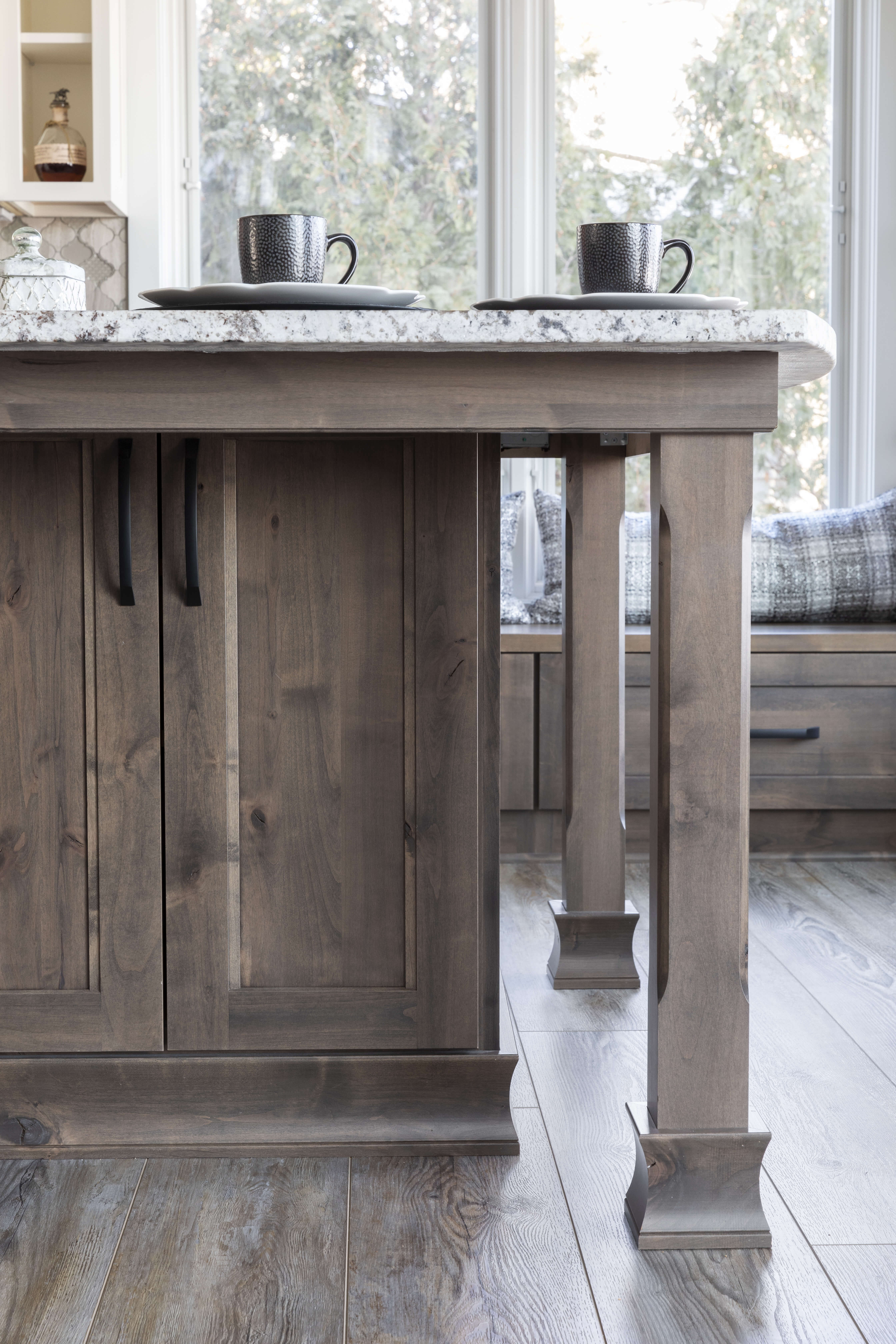 A close up of a kitchen island turned post with a gray stain color.