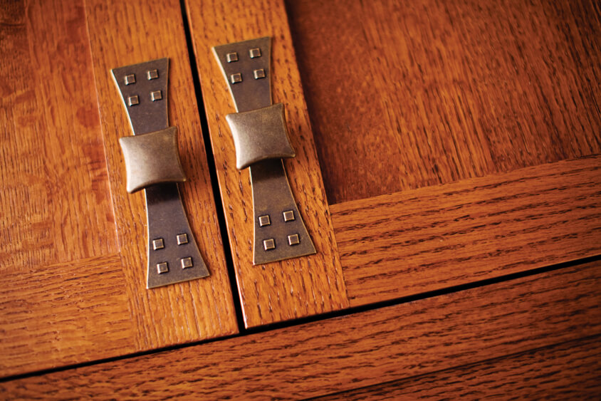 A close up of craftsman styled cabinets with inset cabinet construction and arts and crafts styled hardware with a 4-square motif.