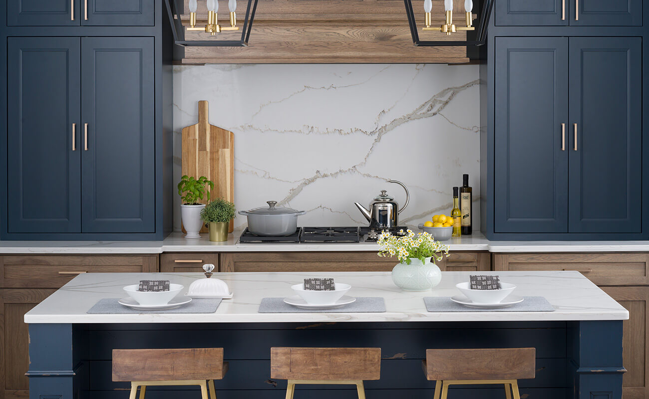 A navy blue and hickory wood kitchen with a modern farmhouse style features Dura Supreme's framed cabinet construction in both inset and full overlay cabinets with the Crestwood Cabinetry product line.