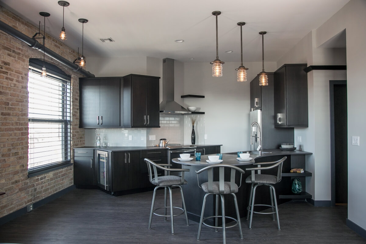 A dark black kitchen with dark stained cabinet from Dura Supreme Cabinetry in an industrial style city loft kitchen design.