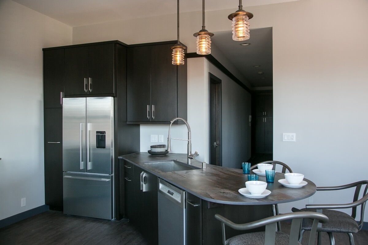 A dark black kitchen with dark stained cabinet from Dura Supreme Cabinetry in an industrial style city loft kitchen design.