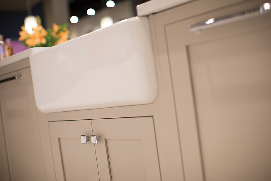 A close up of the detail on an inset kitchen island. The inset cabinet doors are painted with a tan color. An Inset door is installed flush (integrated) within the face frame opening leaving the entire 1 ½” face frame exposed.