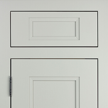 An inset cabinet door with a light gray painted finish and a flat panel style door. A decorative barrel hinge makes a beautiful accent. An Inset door is installed flush (integrated) within the face frame opening leaving the entire 1 ½” face frame exposed. Learn about more cabinet door construction types.