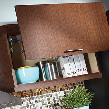 Modern wall cabinet with a lift-up cabinet door on a frameless, full-access cabinet by Dura Supreme Cabinetry. Frameless cabinets offer more accessibility verses framed cabinets. This is due to the fact that there is not an inside edge of a frame projecting into the cabinet opening.