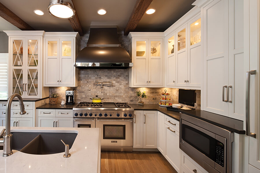 Frameless cabinetry offers flexible styling options. This transitional kitchen design has several tradtional elements on the exterior, but the cabinetry interiors are modern with full-access construction. The kitchen cabinets are painted with a white finish.