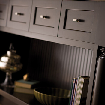 A dark chocolate stained kitchen island cabinet with a row of drawers, a turned post end and an open floor shelf. Which Cabinet Style is Right for You? Learn how to select your cabinetry construction method when shopping for kitchen cabinetry.