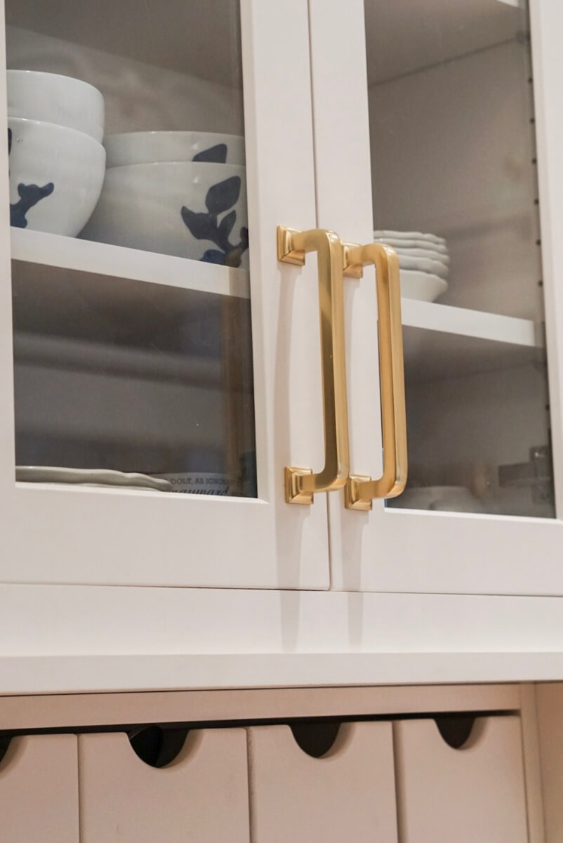 A close up of beautiful white painted cabinet doors with trenyd gold hardware in a traditional styled historic home in Chicago, IL.