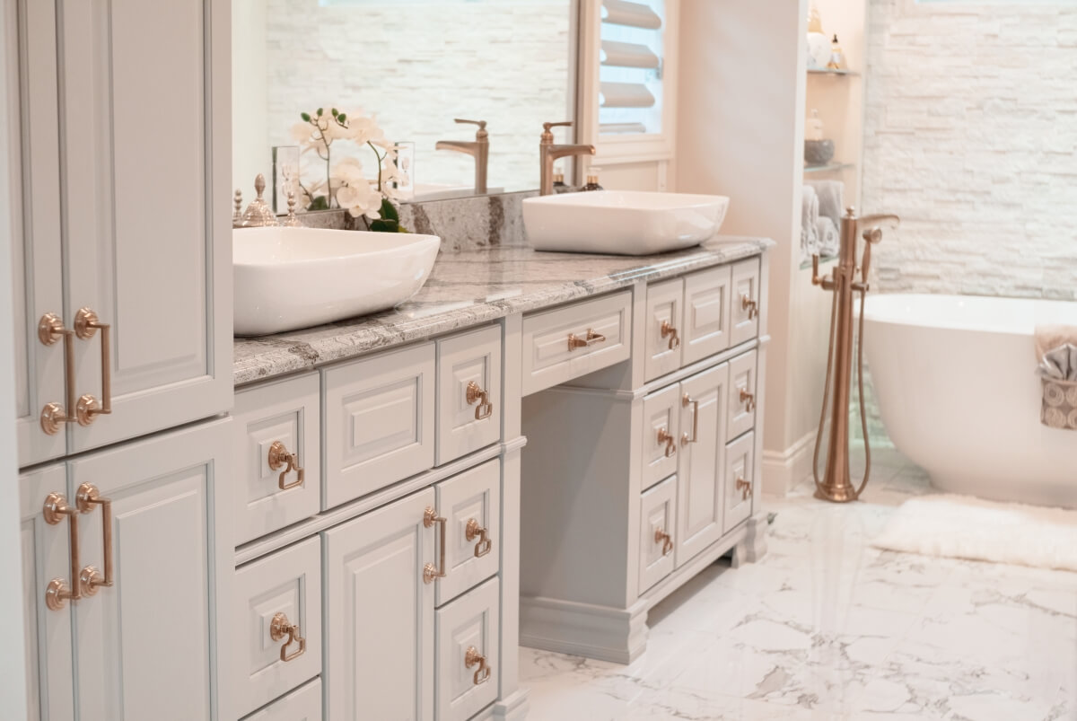 A warm and inviting master bathroom with warm brass hardware and a gray color palette. Showing a close up of the vanity cabinet doors.