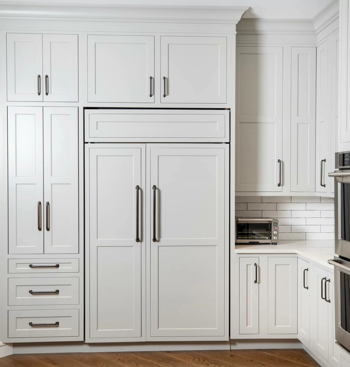 White painted kitchen cabinets and cabinet appliance panels that hide the refrigerator in plain sight.