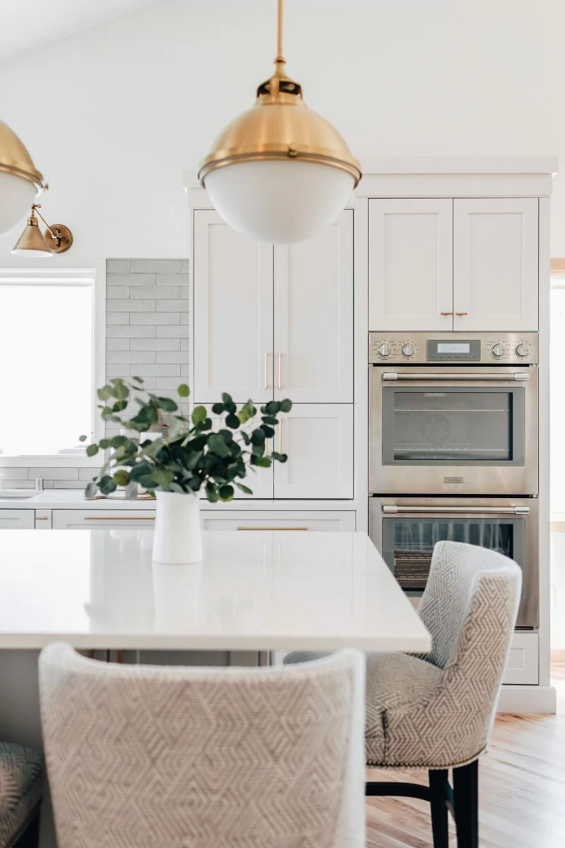 A beautiful all white kitchen with a kitchen island that features counter height seating that is easy for children to reach and sit.