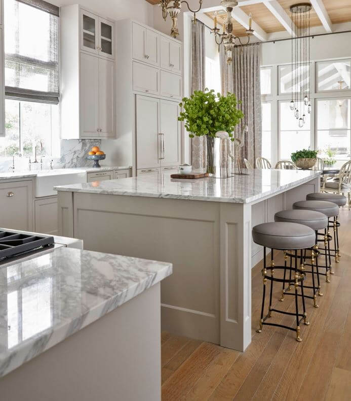 A warm gray painted kitchen design with a large kitchen island with seating for four.