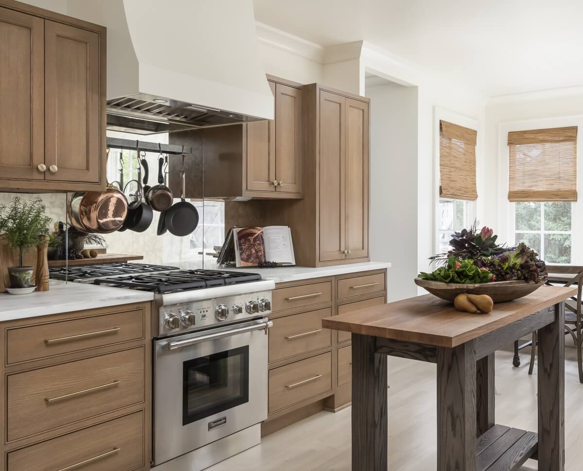 A light natural stained kitchen remodel with a white wood hood and trendy mirrored backspalsh is a bright and fresh design.