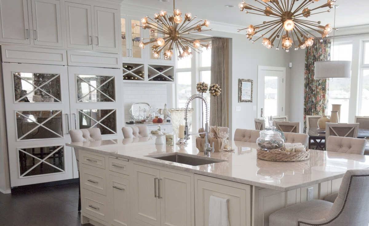 A stunning white and bright kitchen design with mirror cabinet door panels with an X pattern on the refrigerator.