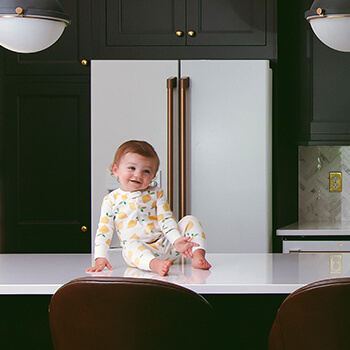 A cute happy baby in a new kitchen with Dura Supreme Cabinetry.