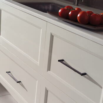 A row of white painted flat panel drawer fronts in a transitional kitchen design. When considering cabinet construction methods, cabinetry is divided into two major categories — Framed and Frameless. What’s the difference between Framed and Frameless kitchen cabinetry? This modern kitchen shows full overlay cabinet doors on frameless construction.