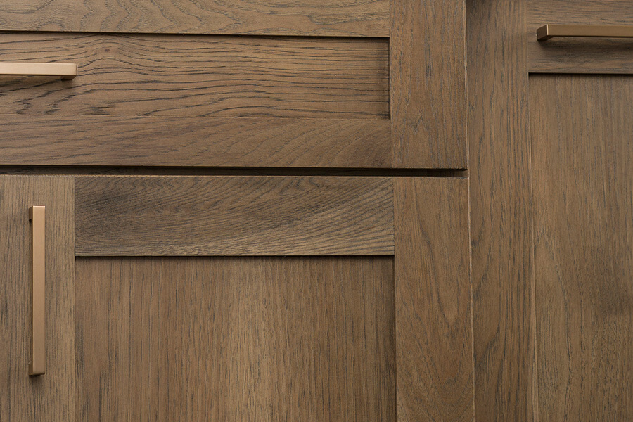 Color trends for kitchen designs are leaning toward brown and gray-brown stains. This close up of kitchen cabinets with a true-brown stained finish and a shaker door style. Brushed brass hardware is shown for the cabinet pulls.