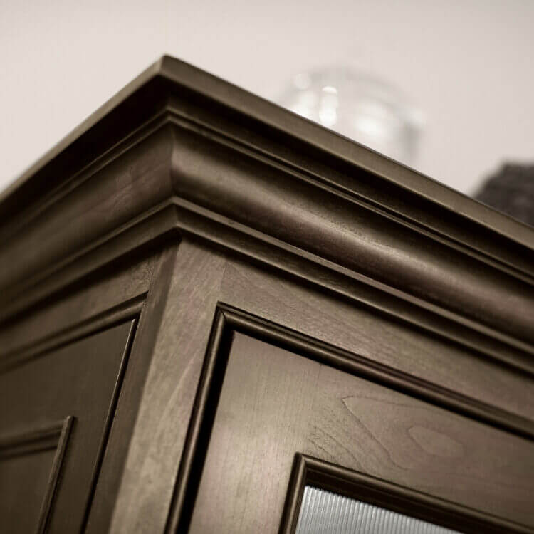 A close up of crown molding on a cabinet with a true-brown stained finish.