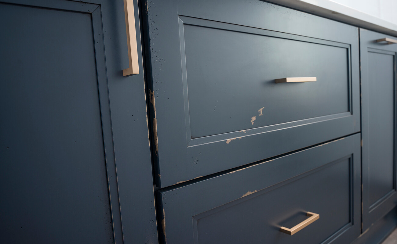 A close up of navy blue painted cabinets with a custom distressed finish from Dura Supreme.