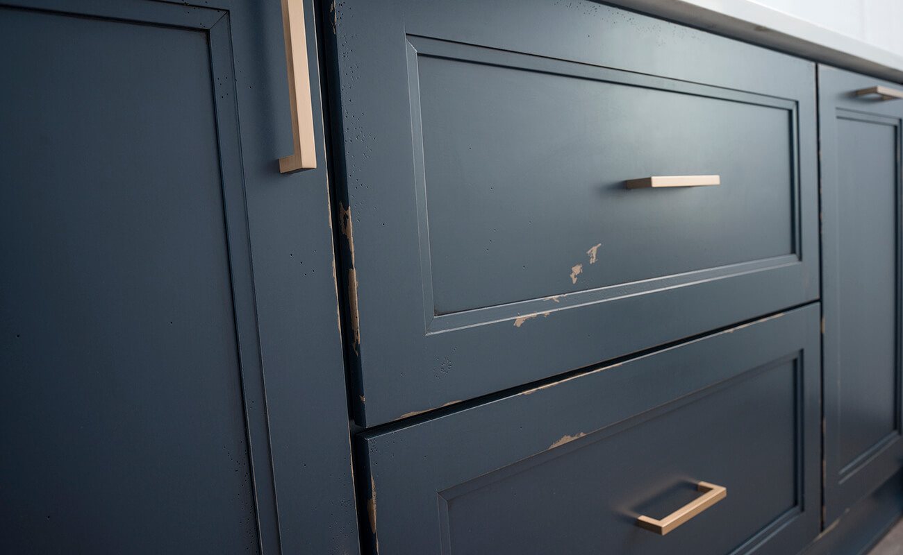 A close up of navy blue painted cabinets with a custom distressed finish from Dura Supreme.