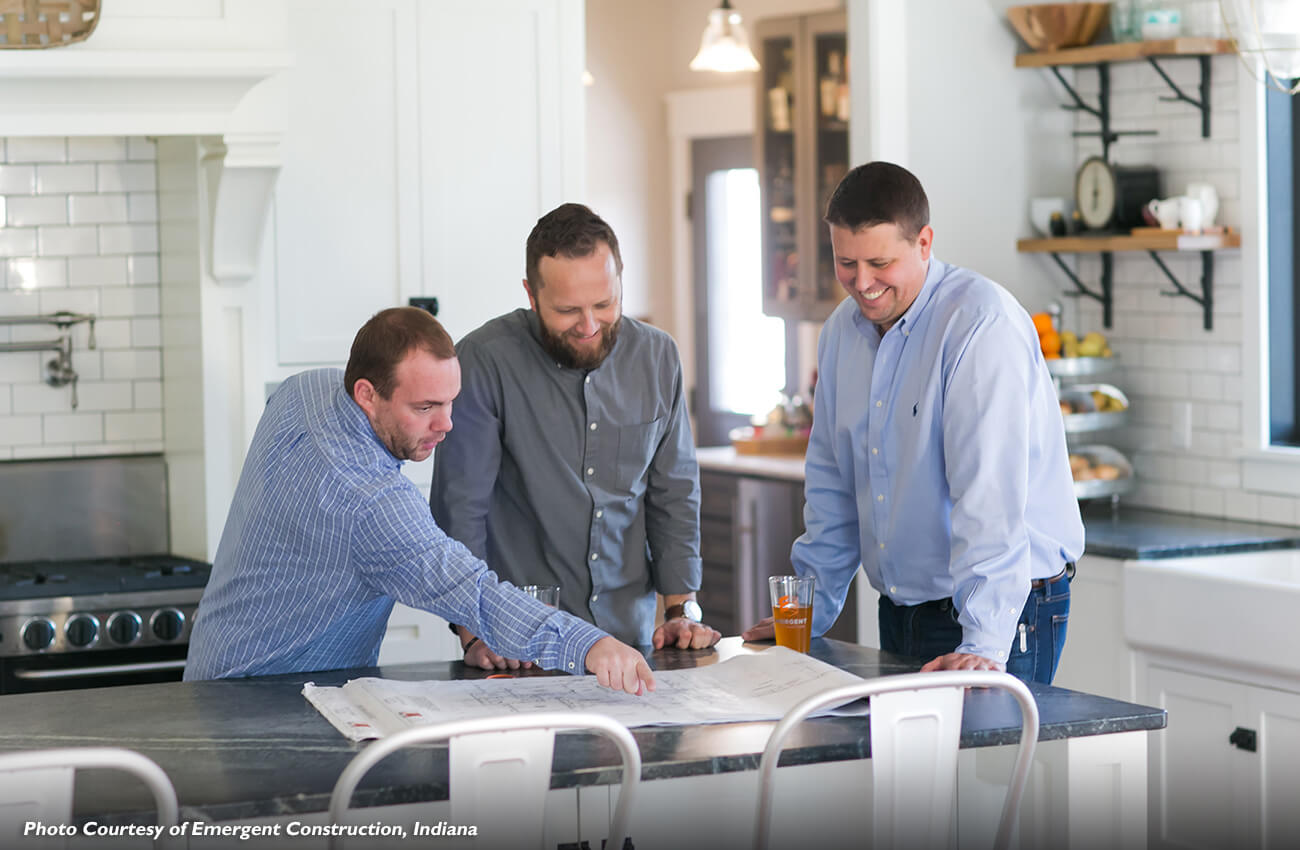 Kitchen and bath designers and custom home builder working together to review blueprints and design a new kitchen with Dura Supreme Cabinetry products.