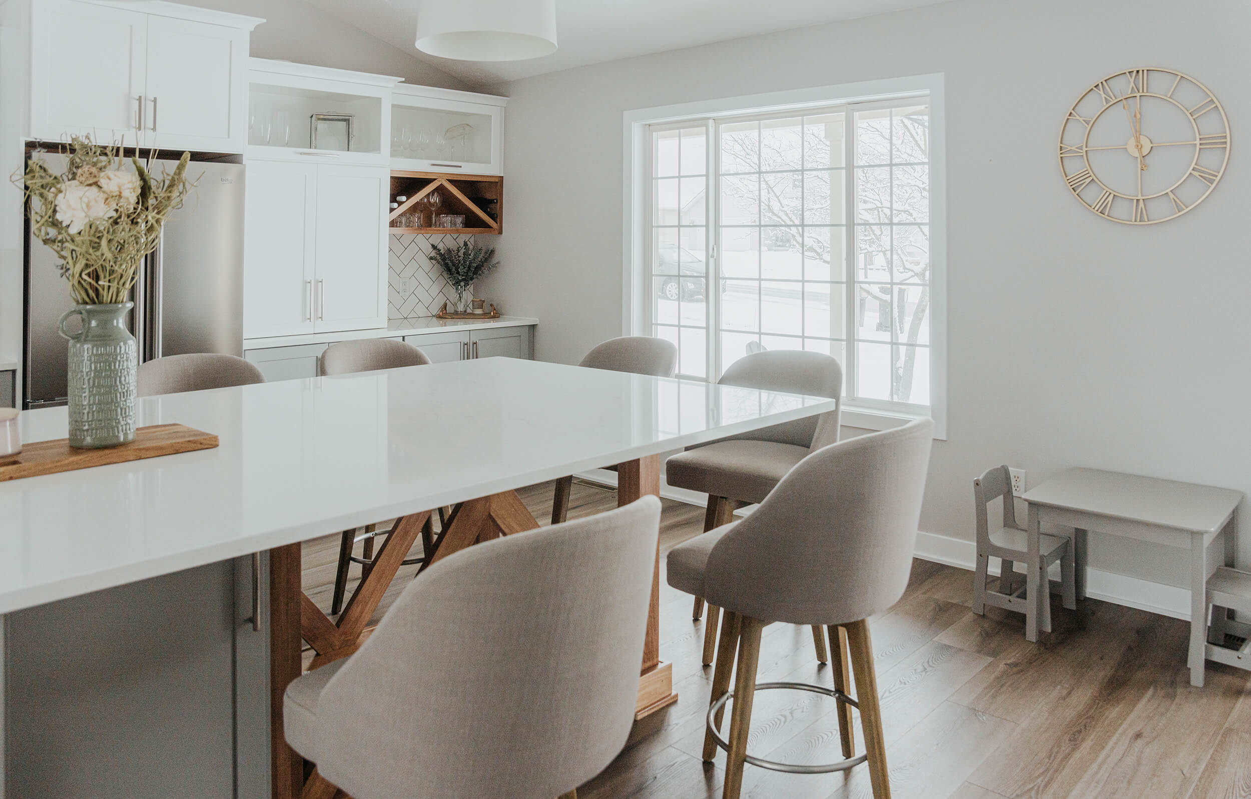 A two-toned Scandinavian style kitchen design with white and light gray painted cabinets accented with light wood finishes for the X-wine rack and X-Endcap on the the kitchen island.