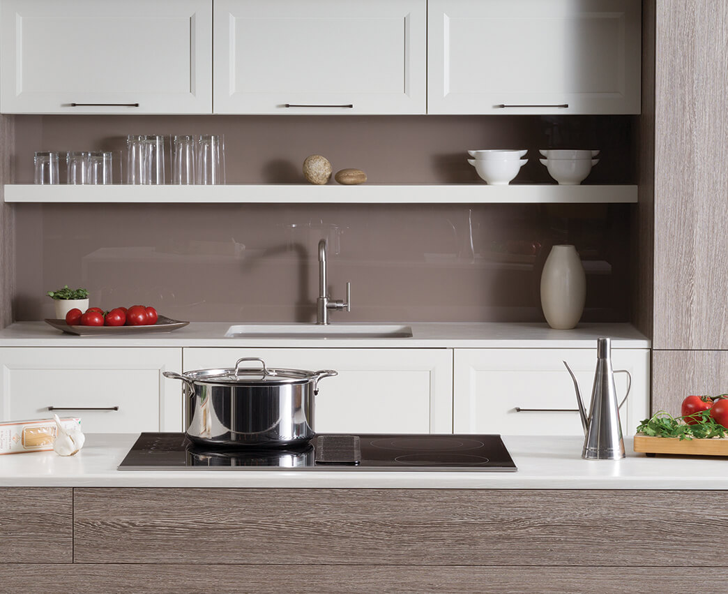 A modern styled Dura Supreme kitchen with an electric cooktop. A modern kitchen with textured foil and white painted cabinets.