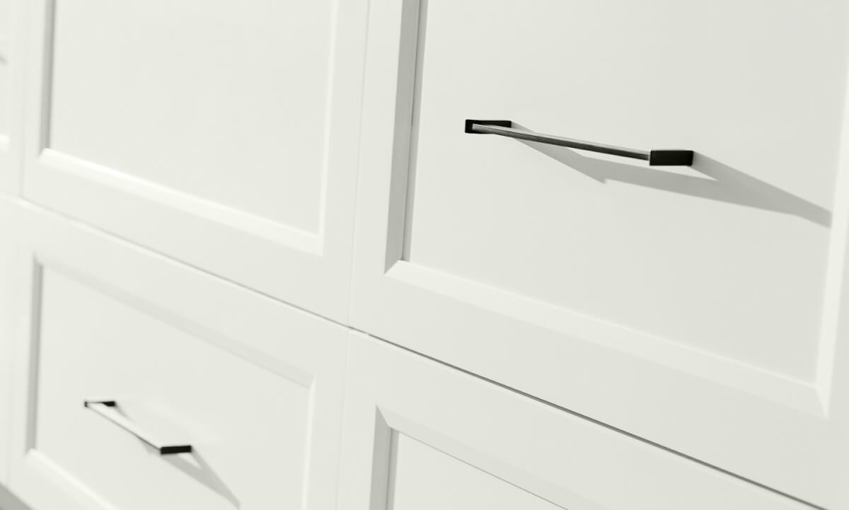 A row of white painted flat panel drawer fronts in a transitional kitchen design. When considering cabinet construction methods, cabinetry is divided into two major categories — Framed and Frameless. What’s the difference between Framed and Frameless kitchen cabinetry? This modern kitchen shows full overlay cabinet doors on frameless construction.