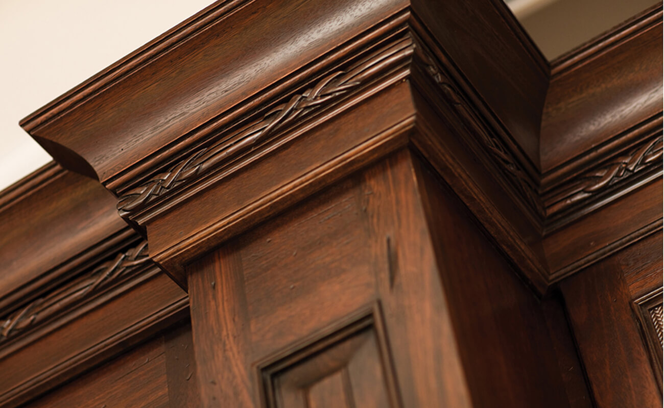 A traditional crown molding stack at the top of wooden cabinets in a traditional styled kitchen.